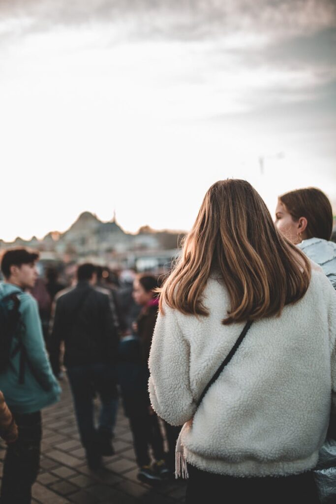 Back view of unrecognizable young female traveler in warm clothes walking along touristic street and sightseeing during vacation